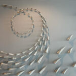 A photograph of a ceramic wall installation of a "flock" of paper airplanes by Jenifer Theom