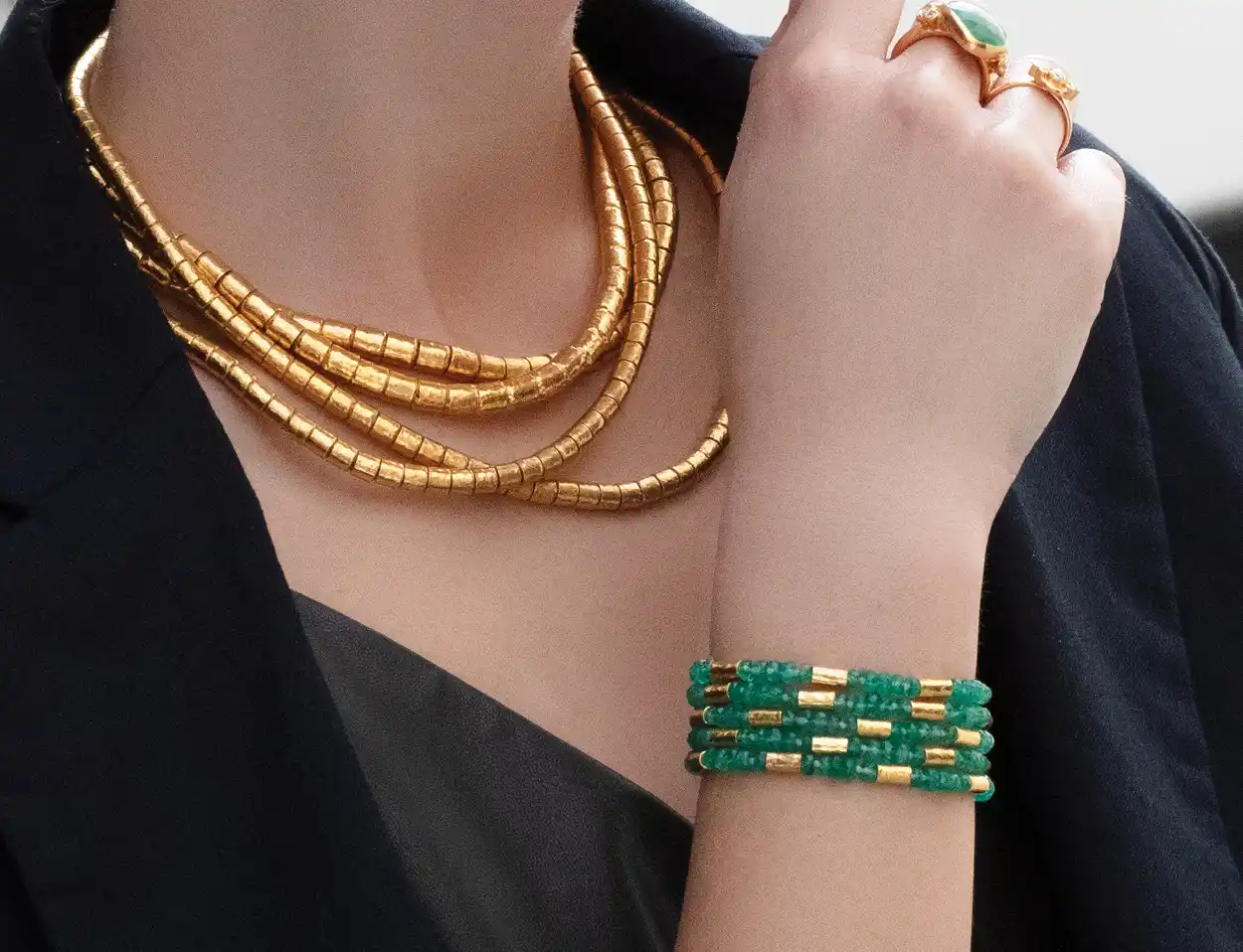 An image of a woman wearing jewelry by Gurhan: necklace, rings, and bracelets.